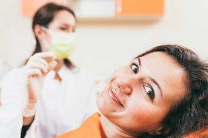 Smiling woman in dental chair finding out about tooth extraction