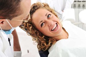 Smiling woman in dental chair asking what is a dental crown and why do I need one